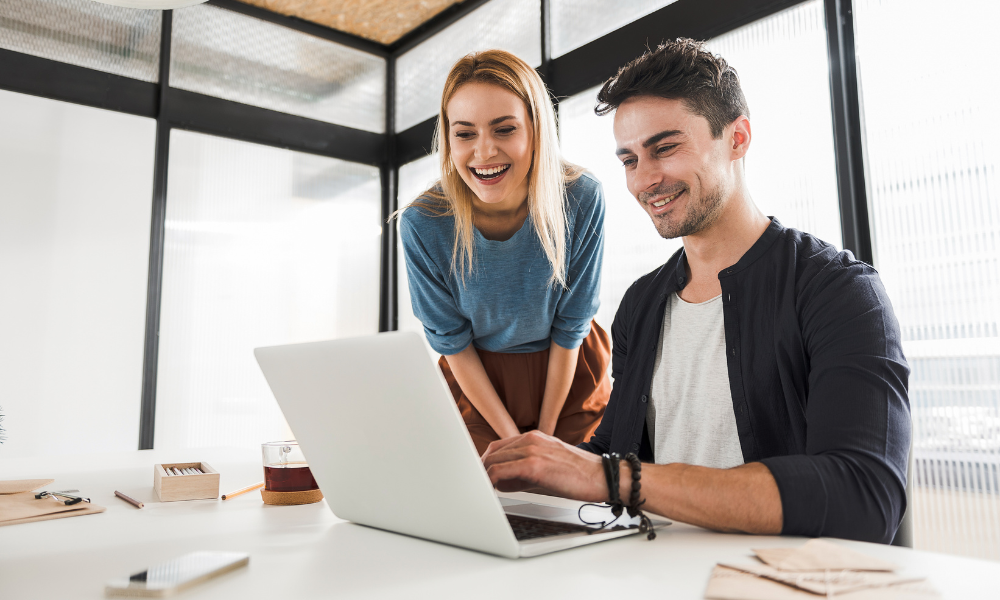 Hombre y mujer sonriendo mientras miran un ordenador