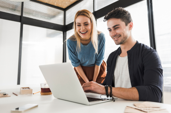 Hombre y mujer sonriendo mientras miran un ordenador